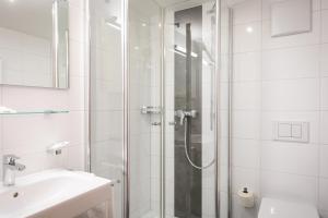 een witte badkamer met een douche en een wastafel bij Café Pension zum Jäger in Buchboden