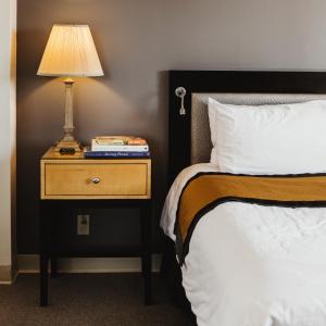 Una cama y una mesita de noche con una lámpara. en Stamford Suites en Stamford