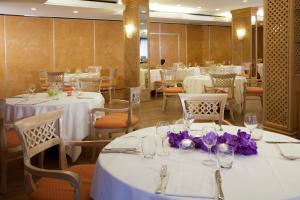 un restaurant avec des tables et des chaises blanches et des fleurs violettes dans l'établissement Starhotels Vespucci, à Campi Bisenzio