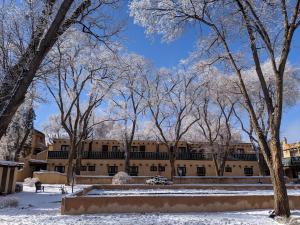 ein Gebäude im Schnee mit Bäumen im Vordergrund in der Unterkunft Sagebrush Inn & Suites in Taos