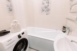 PaulMarie Apartments on Gor'kogo 41 في بابرويسك: حمام ابيض مع غسالة ملابس بجانب مغسلة