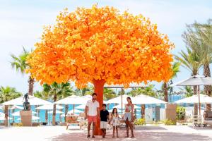 a group of people standing under a large orange tree at Garza Blanca Resort & Spa Los Cabos in Cabo San Lucas