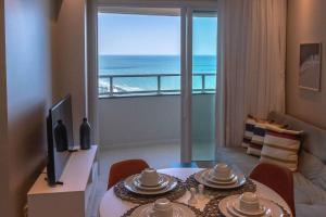 a living room with a table and a view of the ocean at Riviera - 1204 in Natal
