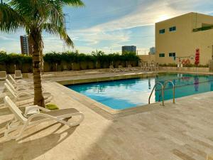 una piscina con tumbonas y una palmera en Apartamento Oceana 52 - Cerca al Buenavista by SOHO, en Barranquilla