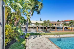 a swimming pool with palm trees and a body of water at By the Sea Villa in Fort Lauderdale