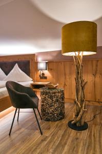 a room with a chair and a lamp and a bed at Wander- und Aktivhotel Adam Bräu in Bodenmais