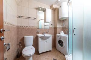 a bathroom with a toilet and a sink and a washing machine at Apartmani Jovan in Budva