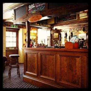 a bar with a wooden counter and a stool at The Copley Arms in East Looe