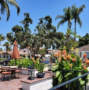 un patio en un hotel con mesas, sillas y palmeras en Marina Beach Motel, en Santa Bárbara