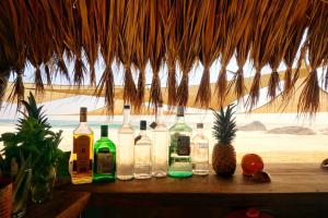 a group of bottles on a table under a straw roof at Casa Corazón San Agustinillo in San Agustinillo