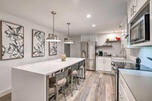 a kitchen with white cabinets and a large island with bar chairs at Cottonwood Heights Apt, 12 Mi to Alta Ski Area! in Cottonwood Heights