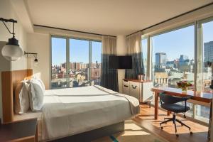 Cette chambre comprend un lit, un bureau et des fenêtres. dans l'établissement Hotel Indigo Lower East Side New York, à New York