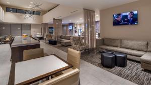 ein Wohnzimmer mit einem Sofa und einem TV an der Wand in der Unterkunft Best Western Plus Executive Residency Rigby's Water World Hotel in Warner Robins