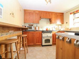 a kitchen with wooden cabinets and a stove top oven at Spring Cottage in Banbury