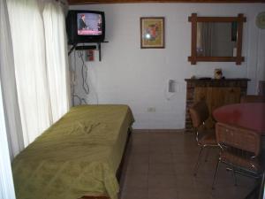 um quarto com uma cama e uma televisão num quarto em Cabaña Las Candelas em Potrerillos