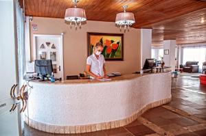 a man standing at a counter in a lobby at Hotel Suiça Faber in Balneário Camboriú