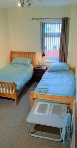 a bedroom with two beds and a window and a table at Grimsby-Cleethorpes Sleeps 7 in Grimsby