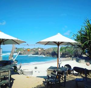 a beach with tables and umbrellas on the sand at D'byas Dream Beach Club and Villa in Nusa Lembongan