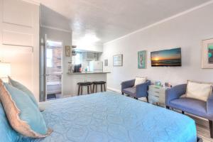 a bedroom with a blue bed and two chairs at Tropic Terrace #15 - Beachfront Rental condo in St. Pete Beach