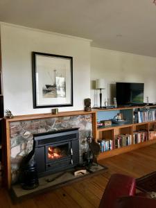 a living room with a fireplace and a tv at The Old Vicarage in Reefton