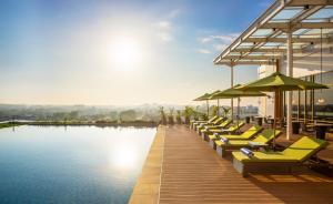 a row of chairs and umbrellas next to a pool at Swiss-Belhotel Solo in Solo