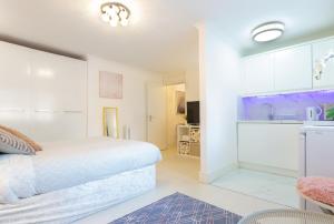 a white bedroom with a bed and a kitchen at Modern apartment close to central London (zone 2) in London