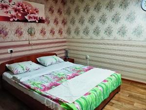 ユジノ・サハリンスクにあるApartment on Pobedy prospekt 75のベッドルーム1室(花柄のベッドカバー付)