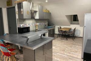 una cocina con electrodomésticos de acero inoxidable, mesa y sillas en Urban Loft en Vesoul