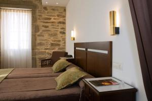 a bedroom with a bed and a table with a book on it at San Francisco Hotel Monumento in Santiago de Compostela