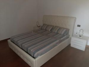 łóżko z paskowym kocem i stolikiem nocnym w obiekcie APPARTAMENTO LAKE GARDA ibiscus di Francia w mieście Desenzano del Garda