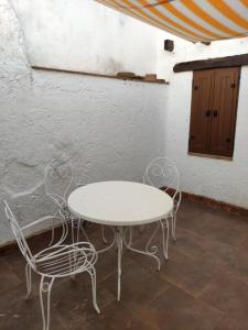 een witte tafel en stoelen naast een muur bij Casa Rural El Trepador Azul in Cabeza la Vaca