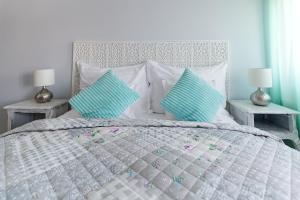 1 cama blanca con 2 almohadas azules y 2 mesas en Aurora Vendégház, en Hévíz