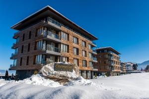 a building in the snow with a sign in front at Cornelia Deluxe Residence in Bansko