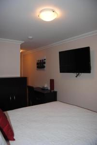 Schlafzimmer mit einem Bett und einem Flachbild-TV an der Wand in der Unterkunft Arnold's Cove Inn in Arnold's Cove