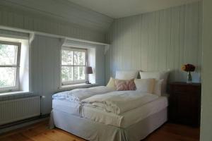 a bedroom with a large white bed with two windows at Altes Fährhaus - Ferienwohnung Boven, 220 qm in Wewelsfleth