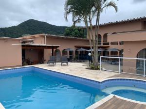 a pool in front of a house with a palm tree at Viva Barê Pousada in São Sebastião