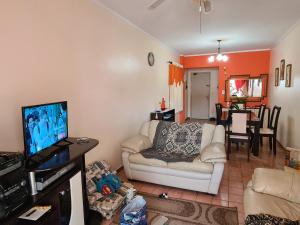 uma sala de estar com um sofá e uma televisão de ecrã plano em Apartamento vista mar Praia Grande em Praia Grande
