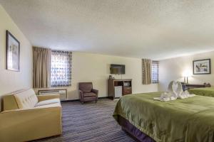 a hotel room with a large bed and a chair at Quality Inn in Grayville