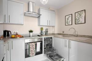 Una cocina con gabinetes blancos y lavavajillas. en Spacious & Cosy, Netflix, Parking, Colindale Station, en Hendon
