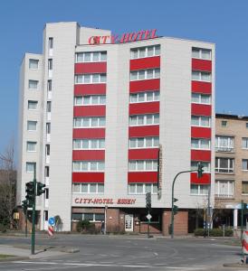 un gran edificio blanco con ventanas rojas y una señal en él en City Hotel Essen, en Essen
