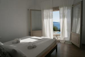 a white bedroom with a bed and a large window at Notus Villa in Chorto