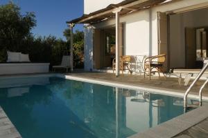 a swimming pool with chairs and a house at Notus Villa in Chorto