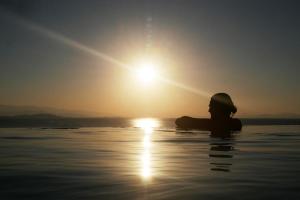 a person sitting in the water at sunset at Notus Villa in Chorto
