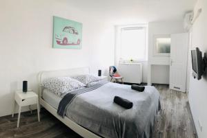 a white bedroom with a bed and a window at Central Apartments in Veszprém