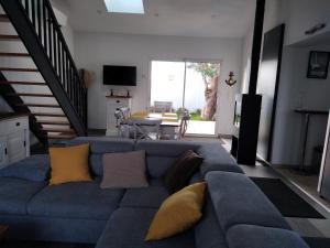 a living room with a blue couch with yellow pillows at OCEANE in Champagné-les-Marais