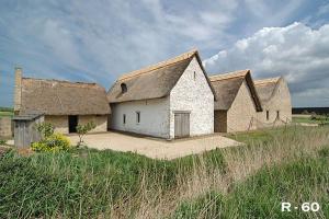 an old building with a thatched roof on a field at les terrasses2 in Ostend