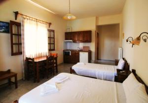 a room with two beds and a kitchen with a table at To Limanaki in Chorefto