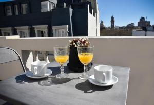 a table with two cups and two glasses of orange juice at Hotel Palacio in Montevideo