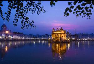 a large building in the middle of the water at night at Hotel Kabir Residency-4 MIN WALK TO GOLDEN TEMPLE in Amritsar