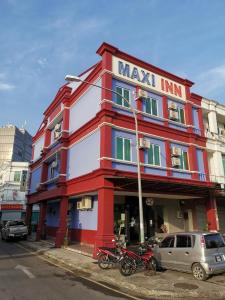 a red and white building with motorcycles parked in front at Maxi Inn in Bintulu